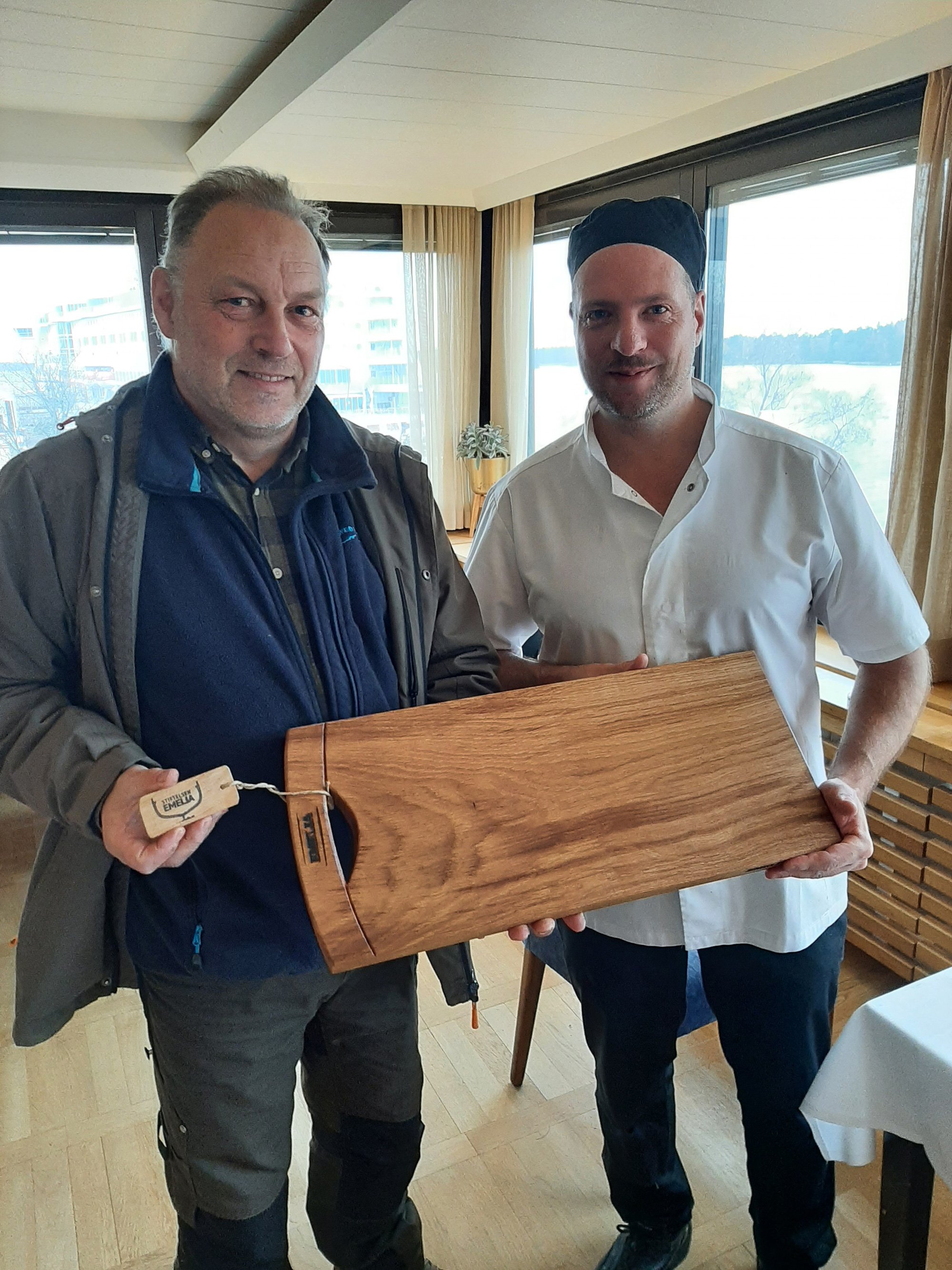 Freddie Olin och köksmästare Peter Sundblom med skärbräda av spillvirke från bygget av Emelia.ax.